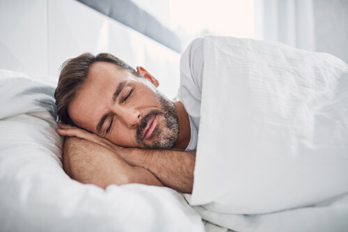 Mann schläft in weißer Bettwäsche